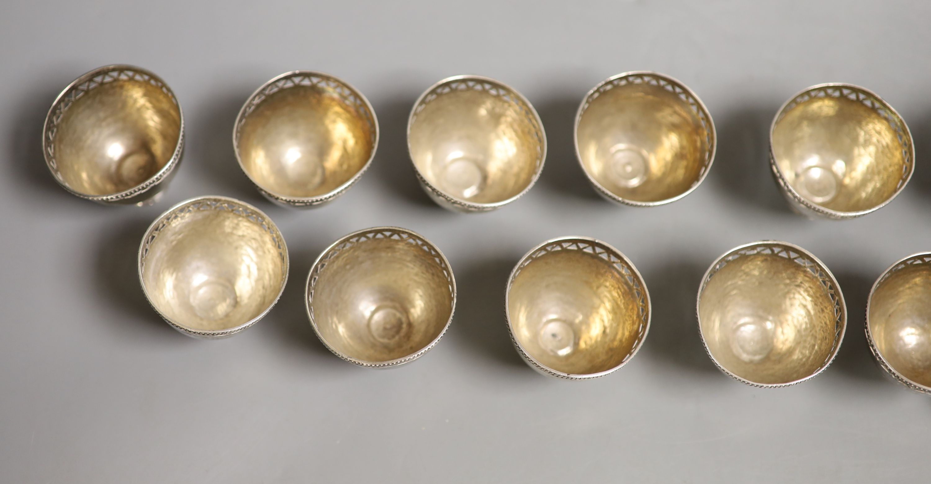 A set of twelve pierced small white metal footed cups